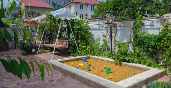 детская площадка с песочницей и качелями в гостинице в Коктебеле с видом на горы.